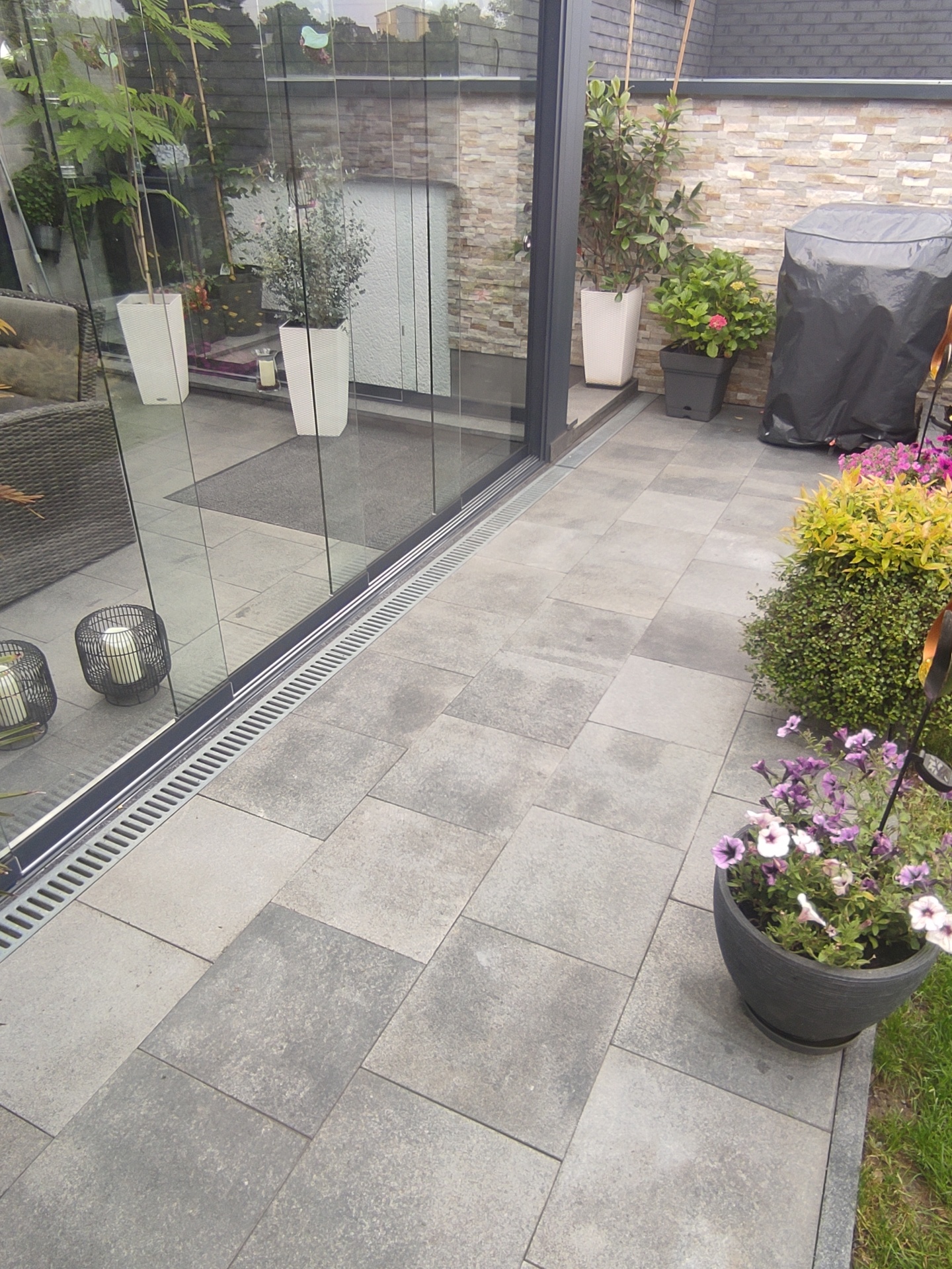 Terrasse mit grauen Granitplatten und Edelstahl-Entwässerungsrinne