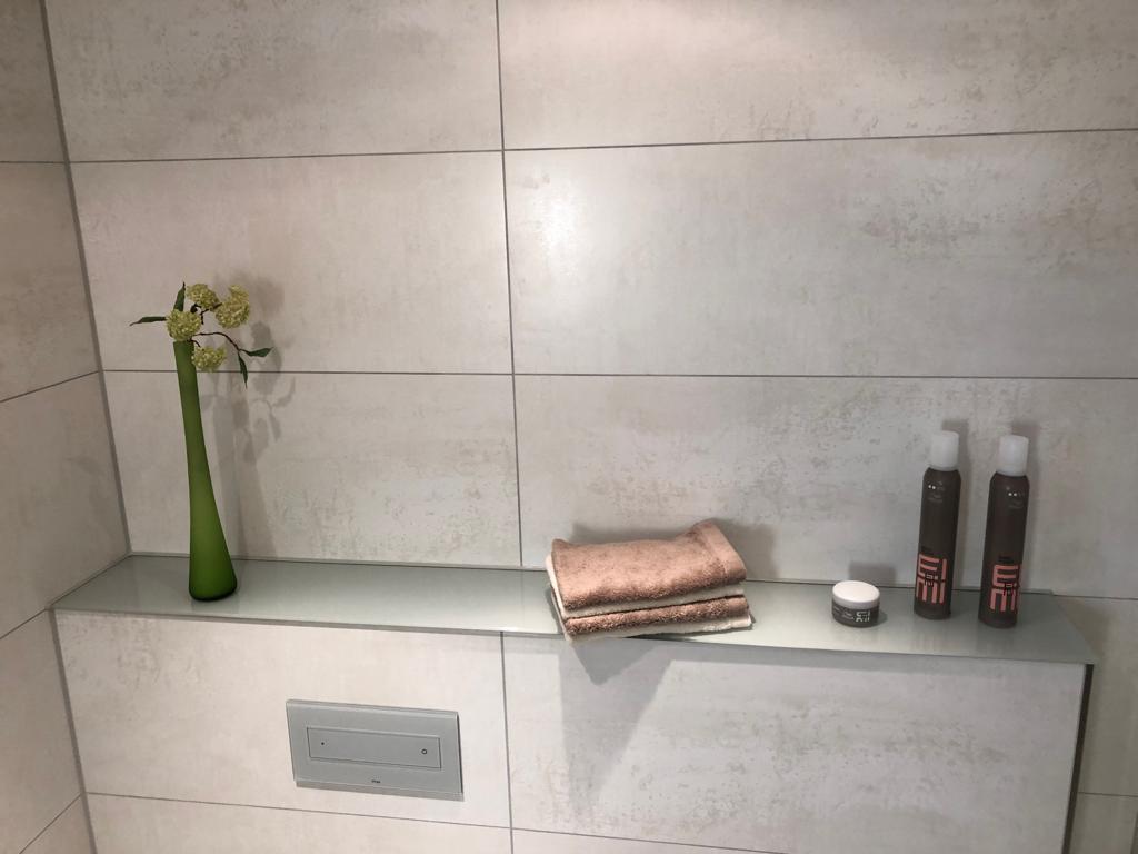 Helle Wandfliesen in Beton-Optik mit Glasablage